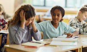 Enfant aidant une de ses camarades en classe